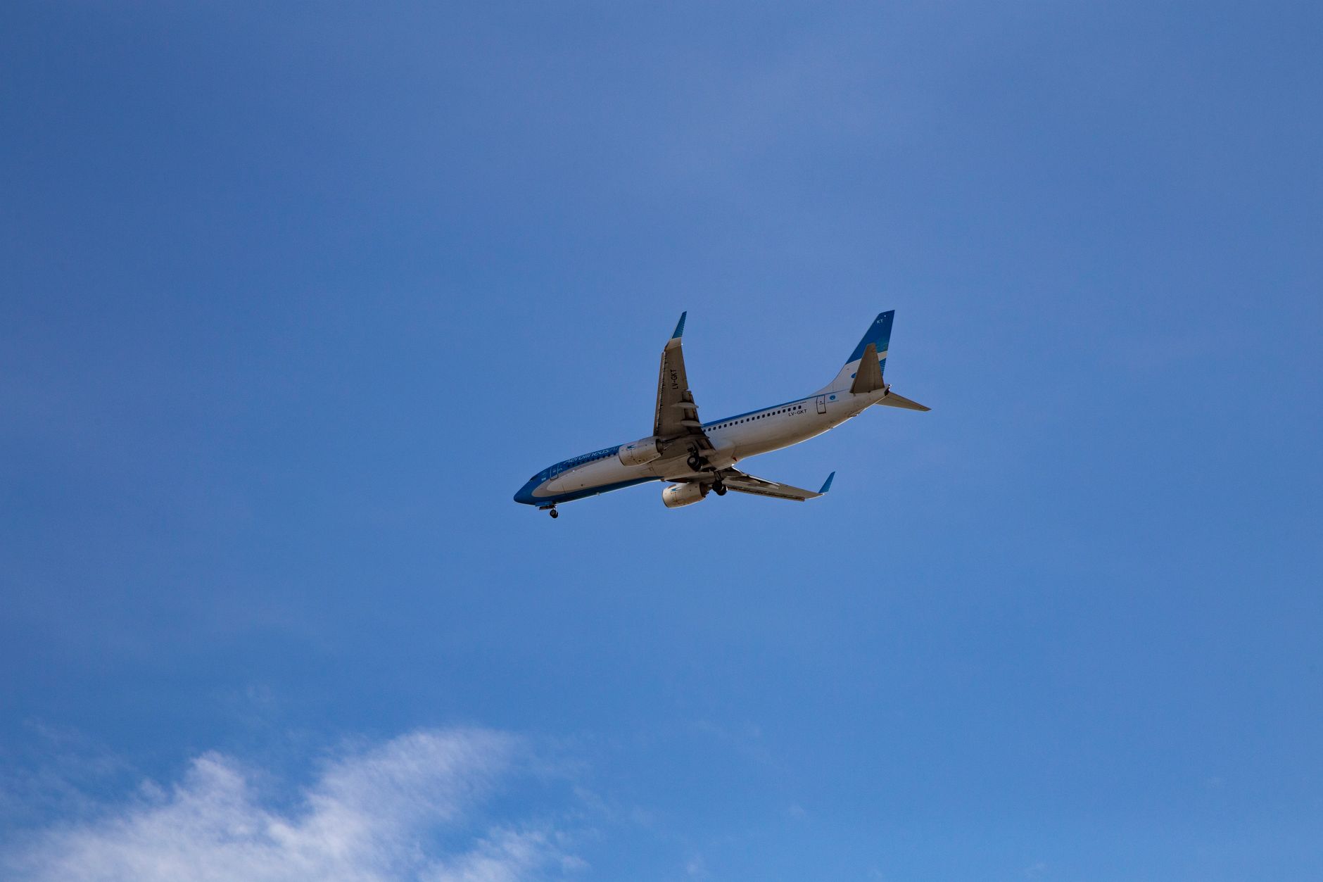 Passenger airplane flying in cloudless blue sky, representing travel and aviation.