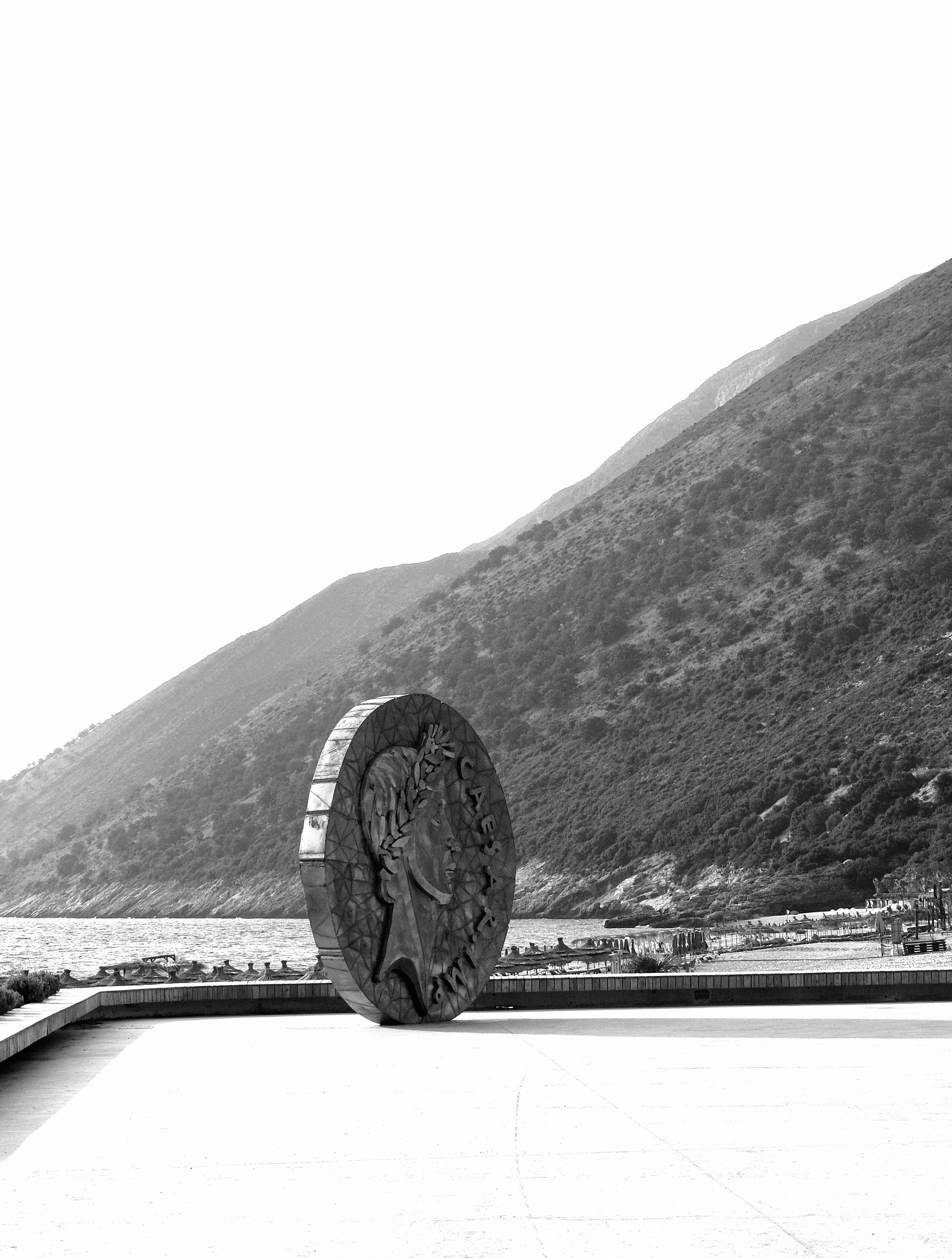 coin statue on sea coast in black and white