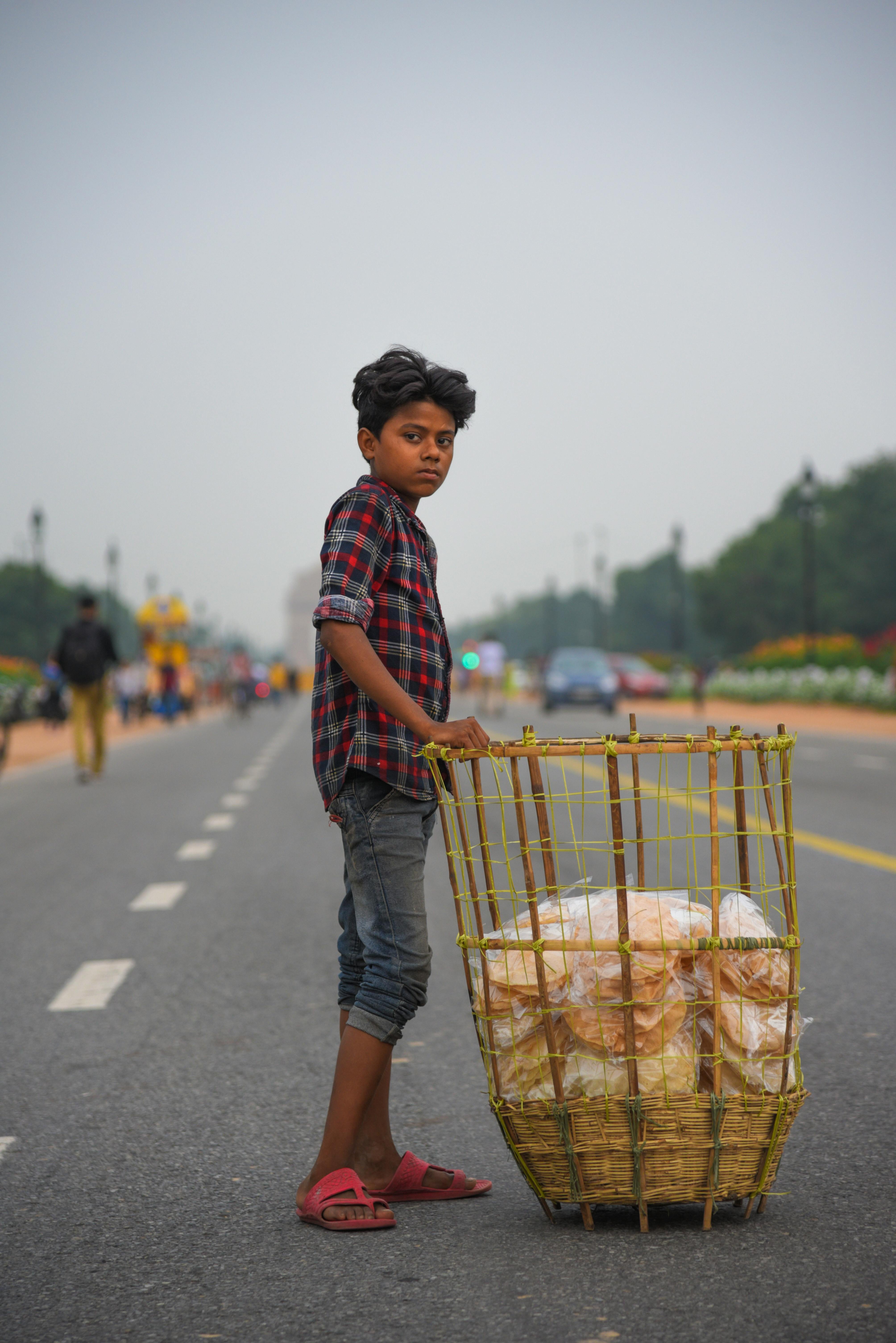 一个拿着篮子的小男孩站在繁忙的城市街道上，展现着街头生活