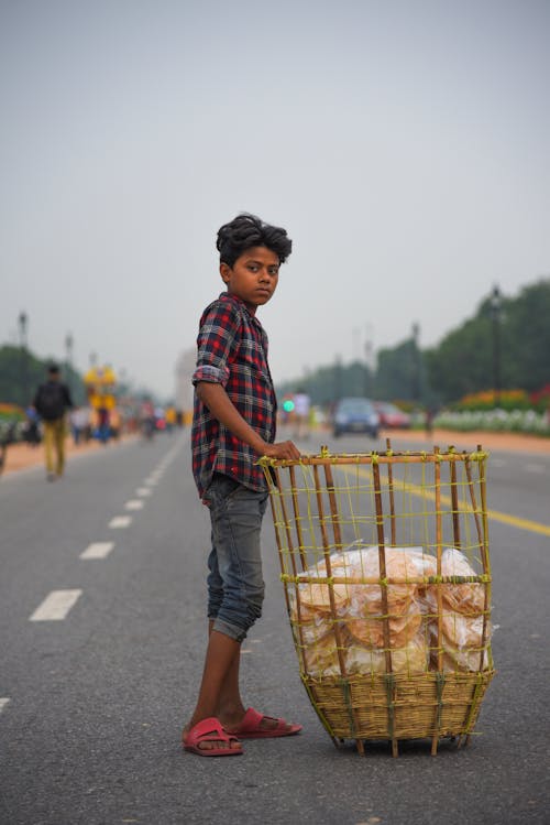 Boy Touching Brown Rattan Basket In The Middle Of Road