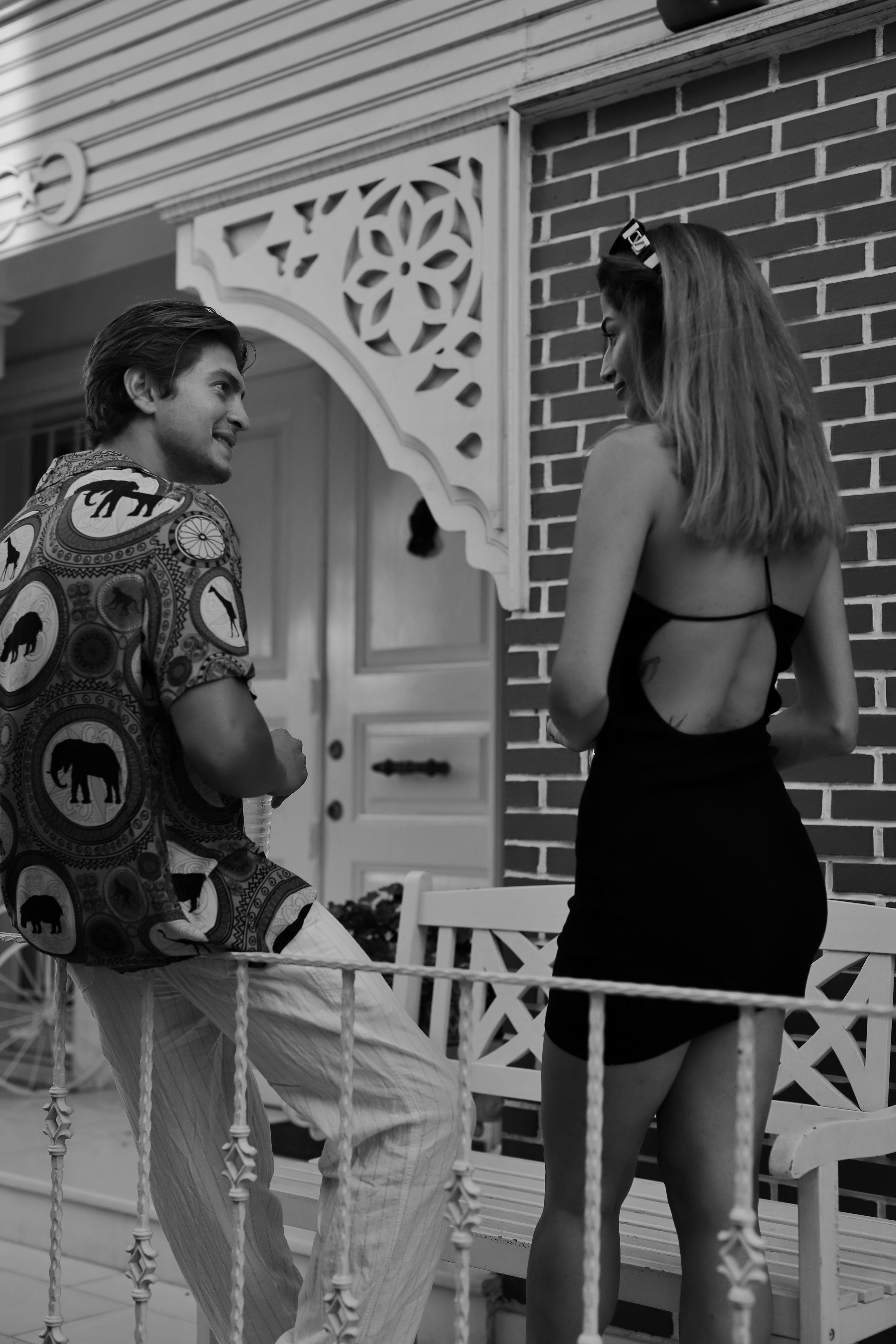 A young couple engaged in conversation, showcasing stylish attire in a casual outdoor setting.