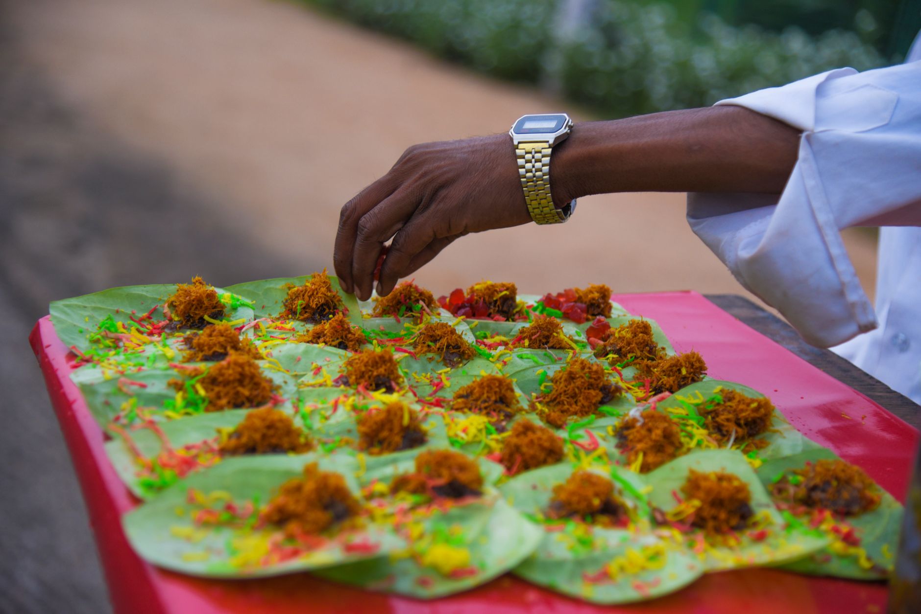 A street vendor prepares colorful paan on a tray, showcasing traditional Indian snack preparation.