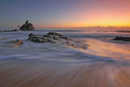 沿海日出令人惊叹，色彩鲜艳，海浪在岩石海岸上流淌