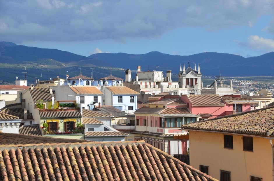 Vista escénica de techos coloridos y casas en Granada, España, con montañas al fondo.
