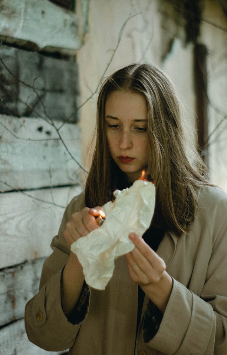 Woman In Green Coat Burning A Crumpled Paper