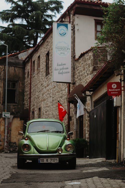 A Vintage Green Volkswagen Beetle Parked on an Alley