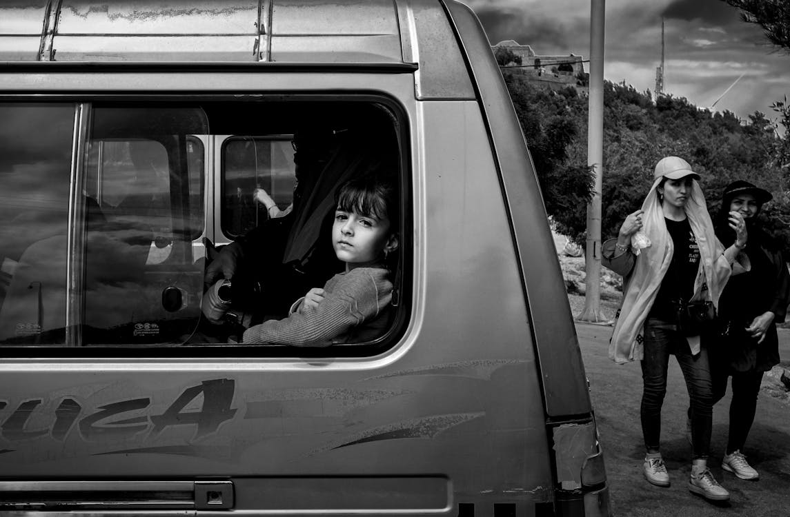 Grayscale Photo of a Girl Inside a Van