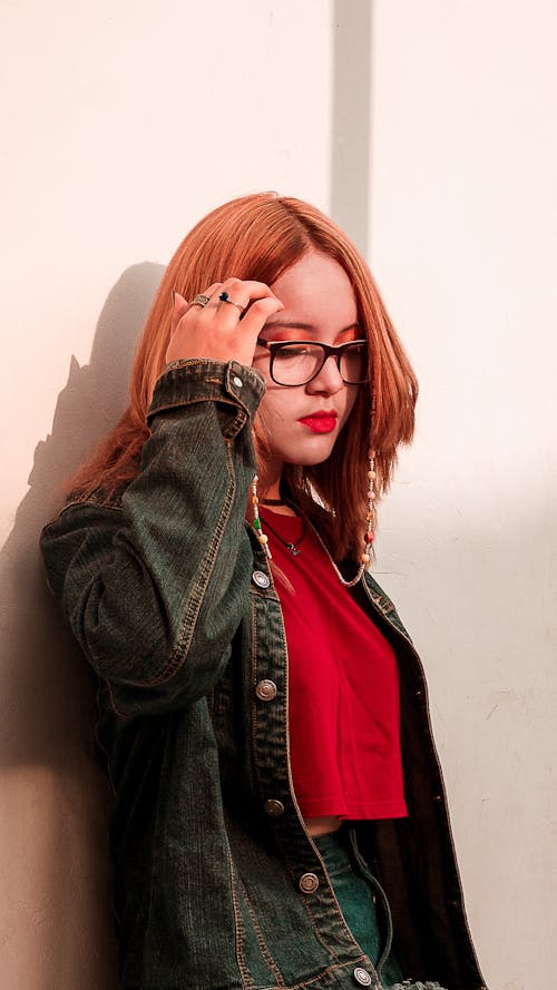 Free Woman in Jean Jacket and Red Crop Top Holding Her Forehead Stock Photo