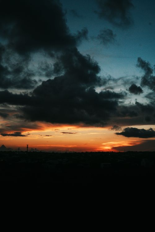 Free Silhouette of Barranquilla skyline under a dramatic sunset and cloud cover. Stock Photo