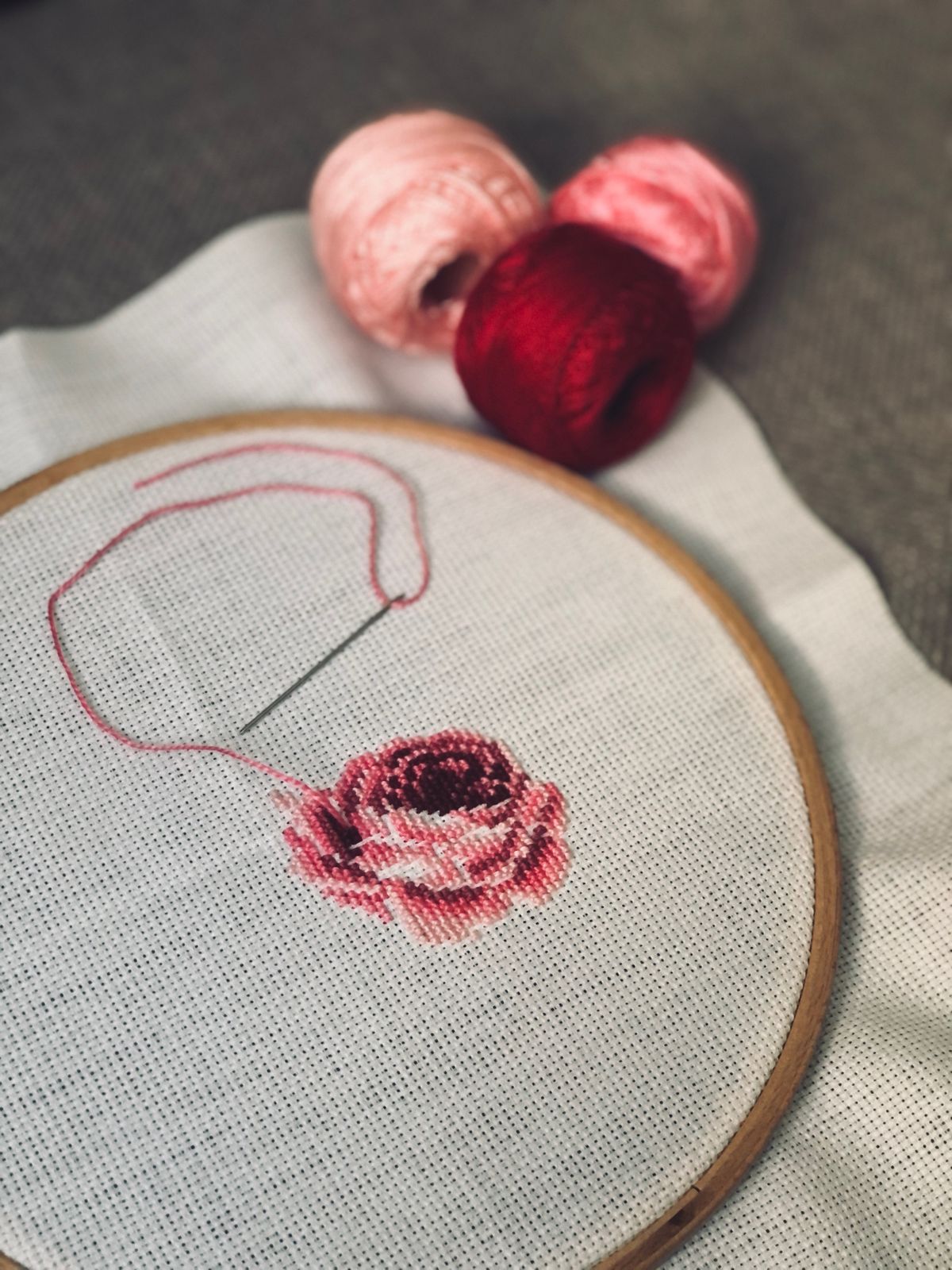 Beginner rose embroidery in a wooden hoop with pink floss