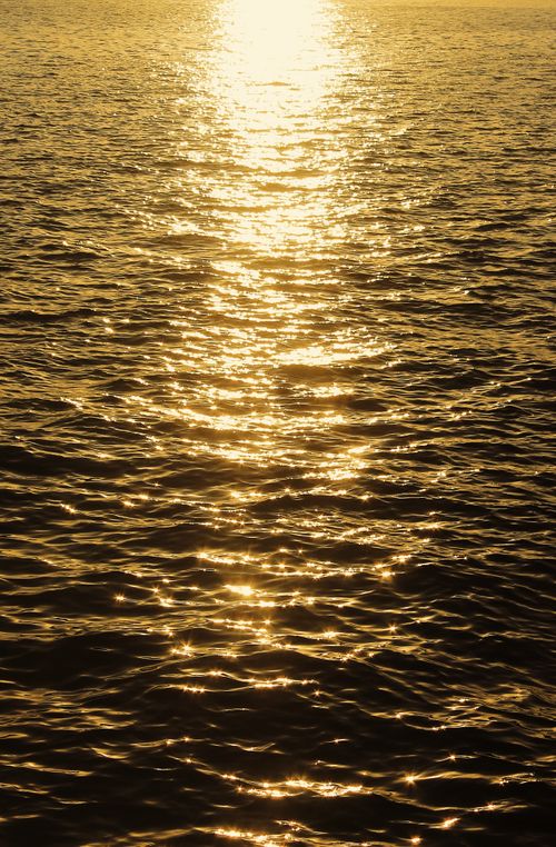 Free Golden sunlight reflects off rippled sea water at sunset, creating a tranquil and mesmerizing view. Stock Photo