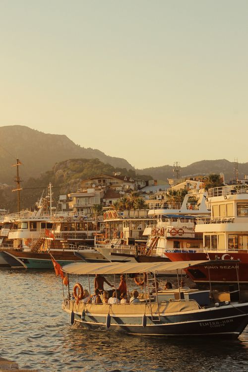 Free A serene harbor scene with multiple boats and yachts at sunset, capturing a tranquil travel mood. Stock Photo