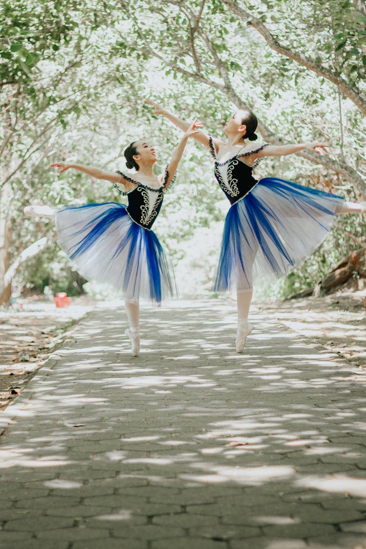 Ballerinas Dancing On The Street Between Green Trees