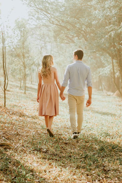 Woman and Man Walking on Holding Hands