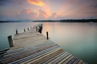 黎明时分，木制码头伸向平静的水面，天空与倒影相映成趣