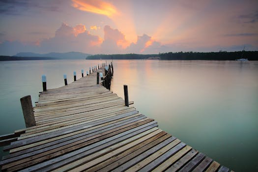 黎明时分，木制码头伸向平静的水面，天空与倒影相映成趣
