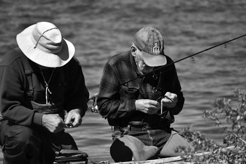 Man in Black Jacket and White Hat Fishing on Lake