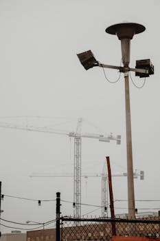 Vertical shot of a construction site with cranes and streetlight, showcasing urban development.