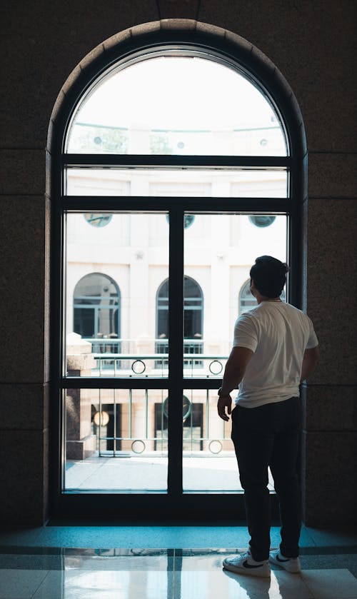 man Standing Beside a Glass Window