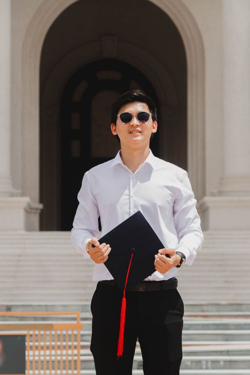 Free A young man wearing sunglasses stands outside with a graduation cap and diploma in Phnom Penh, Cambodia. Stock Photo