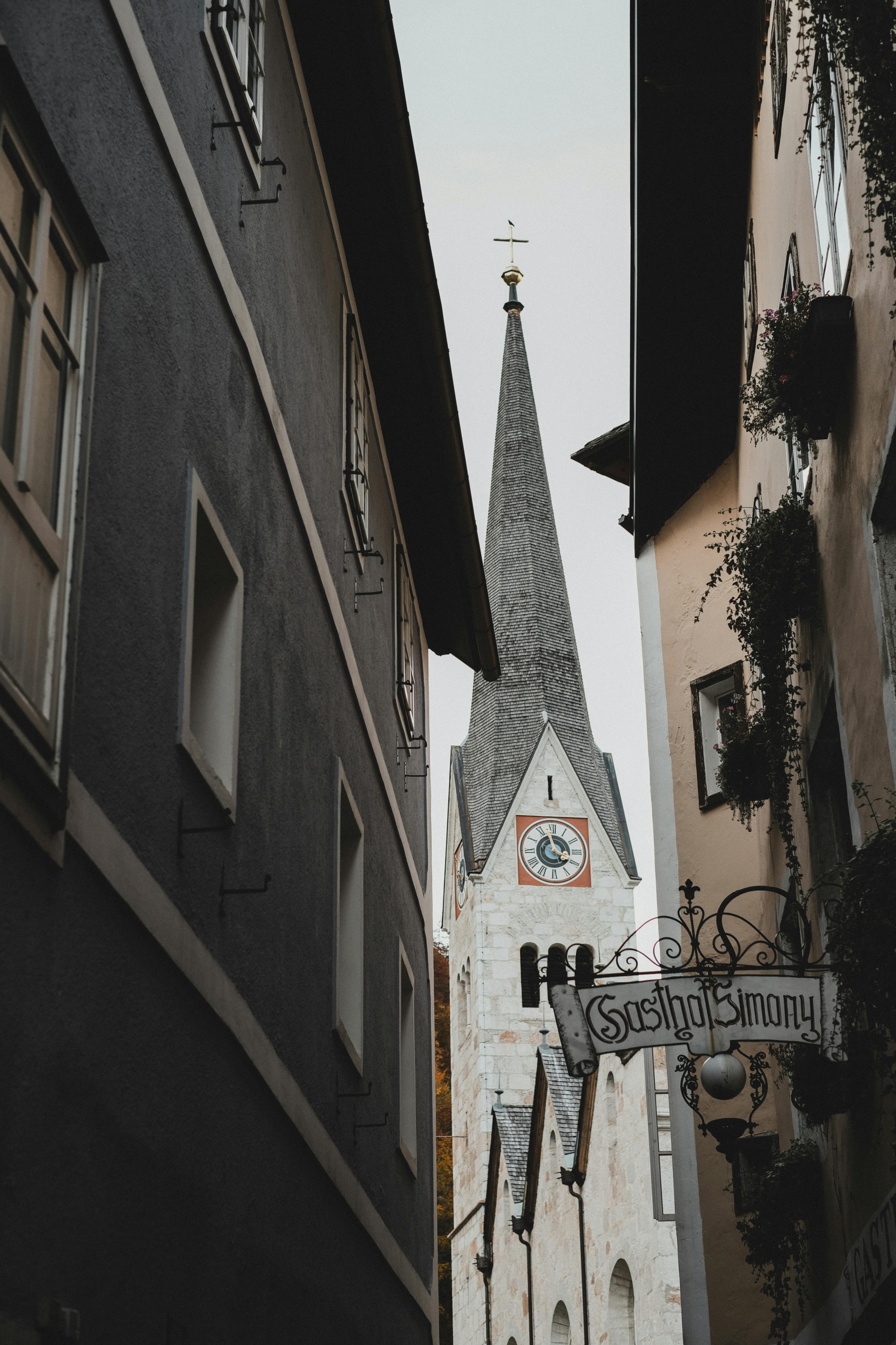Dramatic view of the Hallstatt Lutheran Church tower framed by narrow streets in Austria.