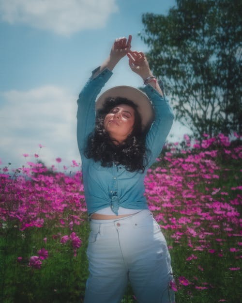 Woman Raising Her Hands in Denim Long Sleeve and White Shorts Posing on a Flower Field