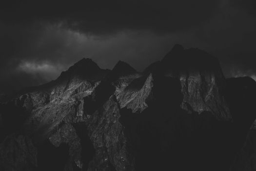 A captivating black and white photo of towering rocky mountain peaks under a moody sky.