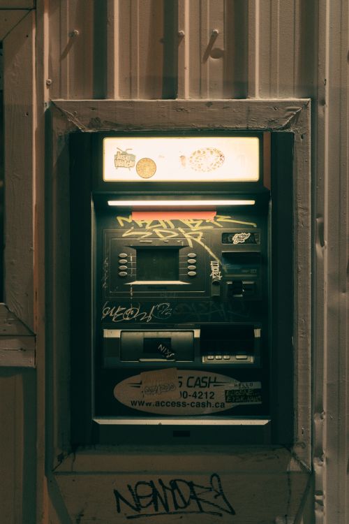 Free Close-up of an ATM covered in graffiti on a nighttime city street. Urban art concept. Stock Photo