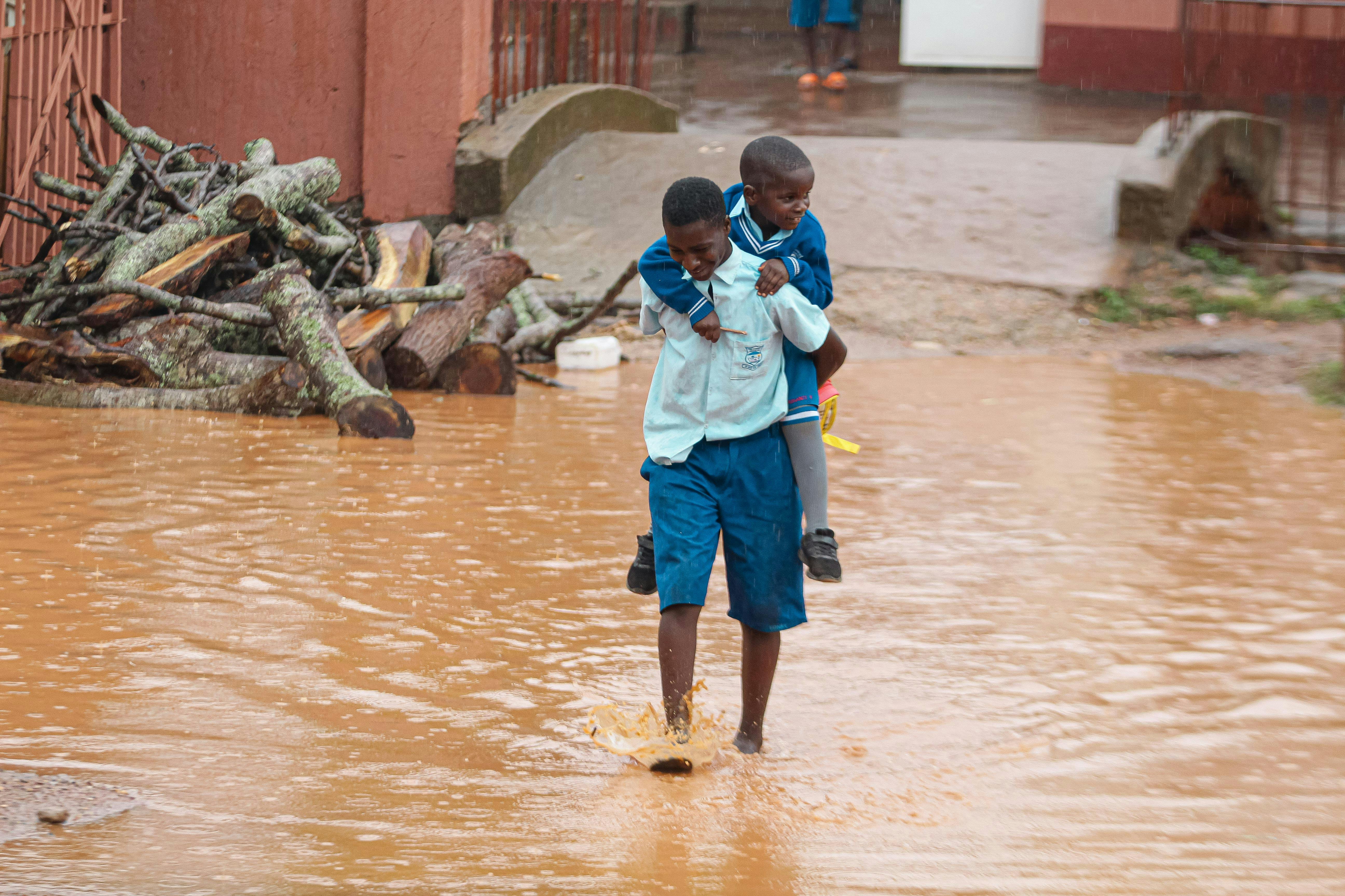 man in blue skirt and blue shorts carrying a boy in blue jacket while walking on water