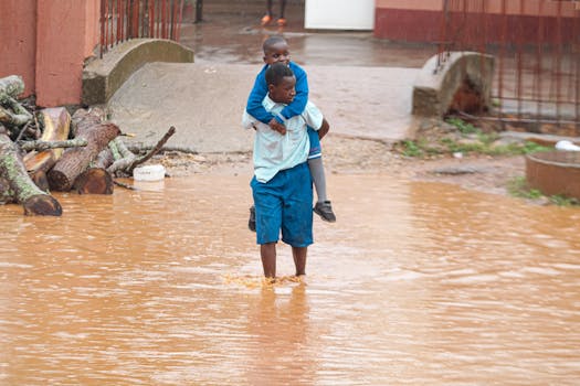 Two children navigate a flooded street with resilience and cooperation after heavy rains.