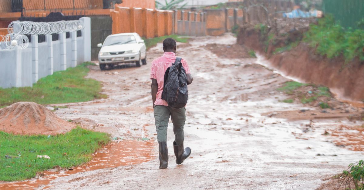 Muddy unpaved road leading to Christ Embassy Ho Loveworld Arena with people walking