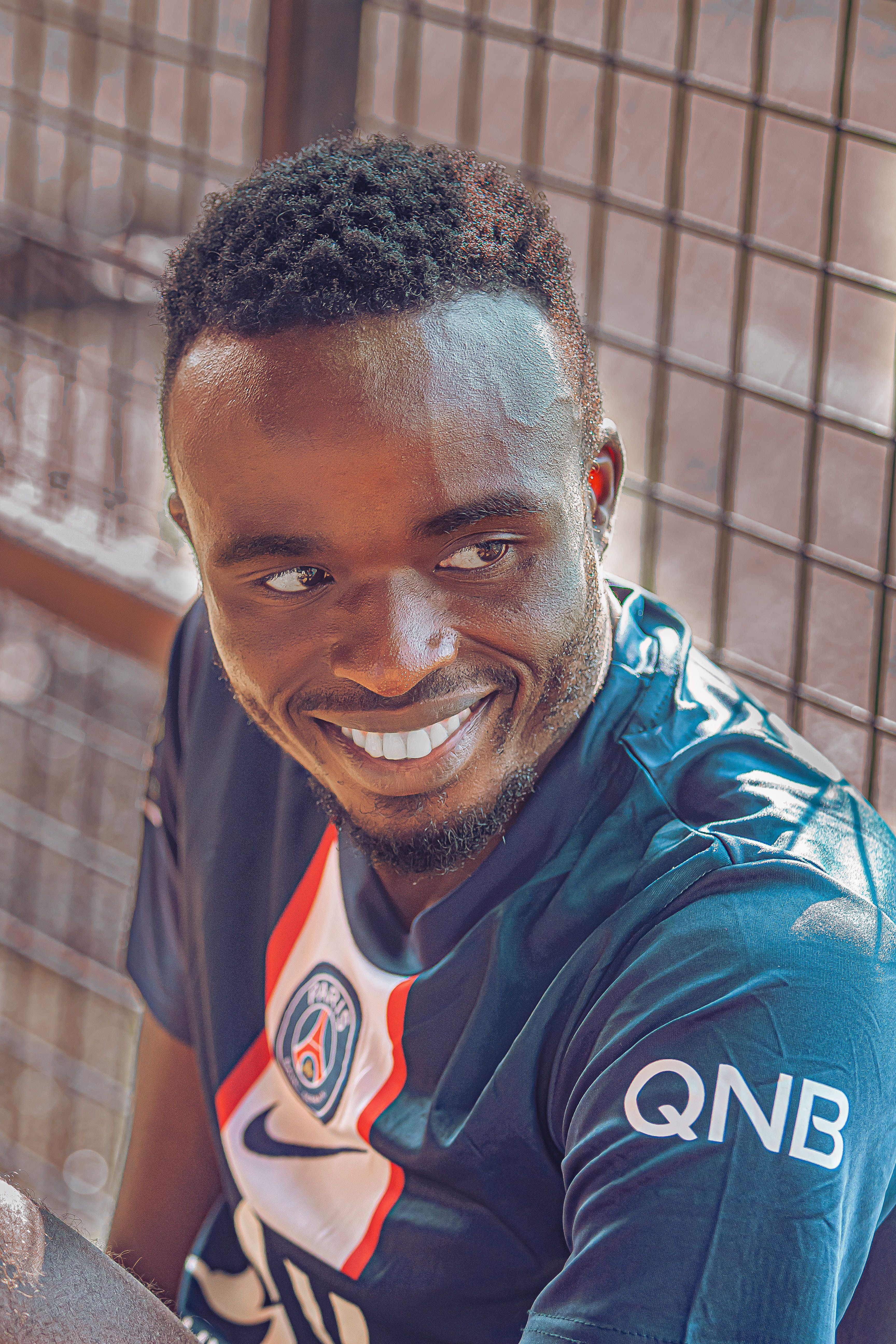 Portrait of a smiling man in a soccer jersey with sunlight.