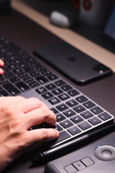 Hand typing on sleek black keyboard on a modern workspace desk.
