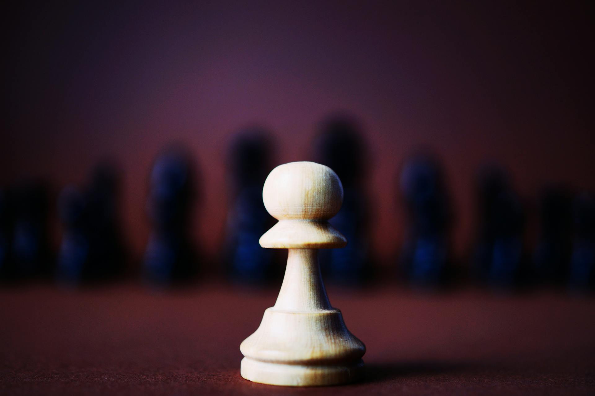 A detailed close-up of a wooden chess pawn against a blurred background, representing strategy.