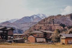 Scenic view of a traditional Japanese village with mountains in the background during winter.