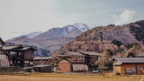 Scenic view of a traditional Japanese village with mountains in the background during winter.
