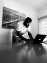Grayscale Photo of a Man in Black Shirt Using His Laptop