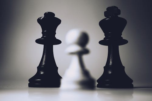 Selective Focus Photo of Two Black Chess Pieces