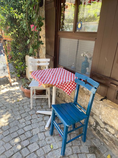 Free Rustic outdoor cafe setting with wooden chairs and cobblestone walkway in summer. Stock Photo