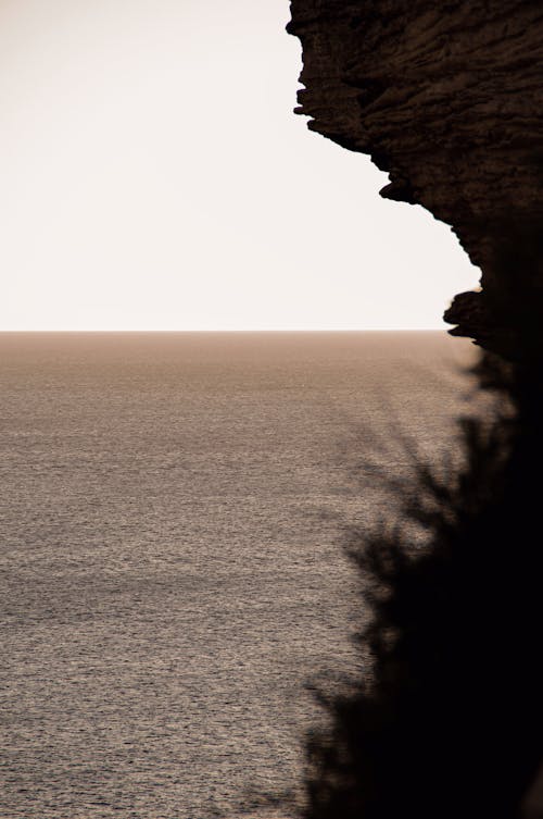 Silhouetted Rocky Cliff and View of a Sea at Sunset