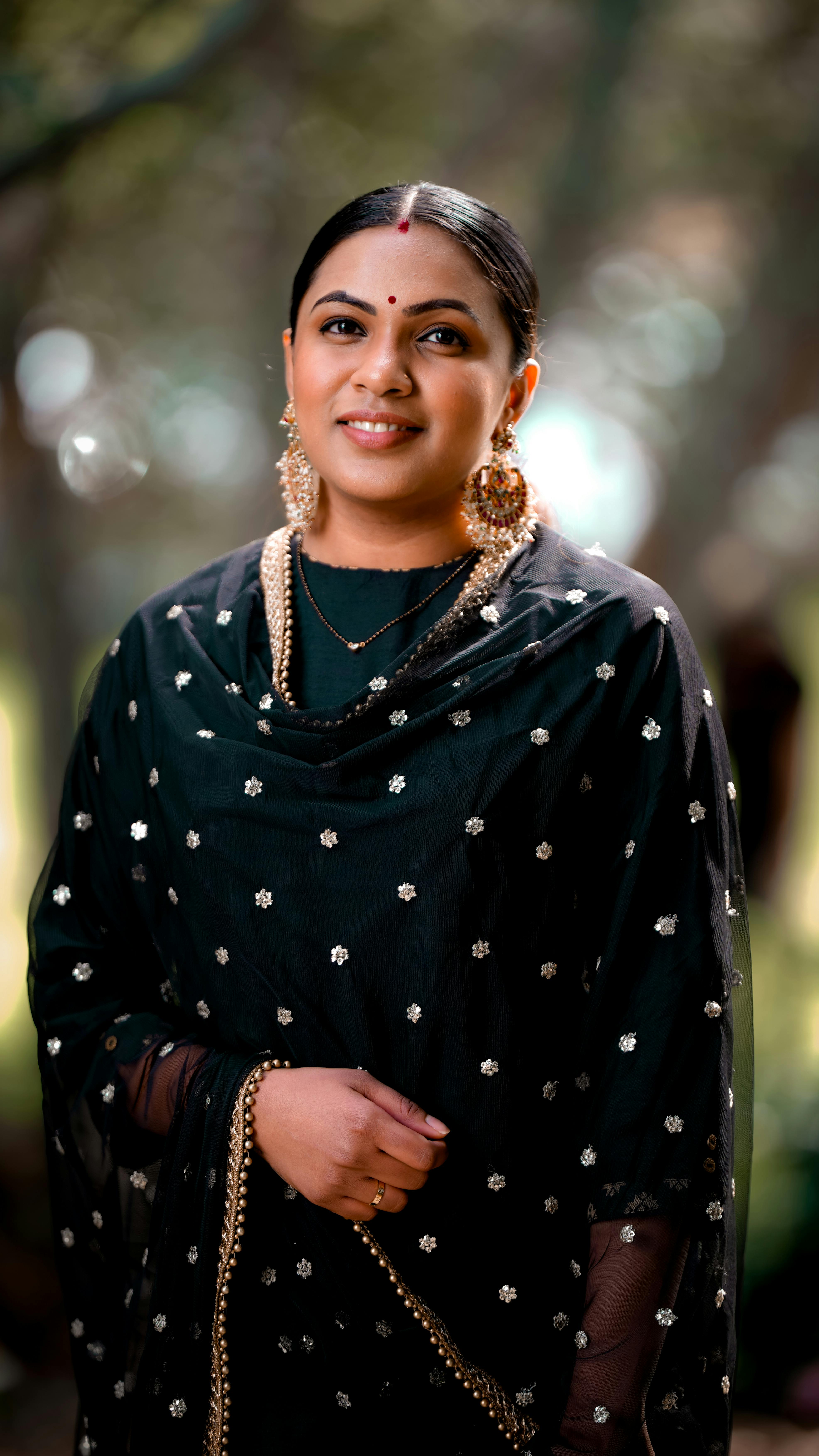 Portrait of a smiling Indian woman in traditional attire with a bindi and shawl, outdoors.