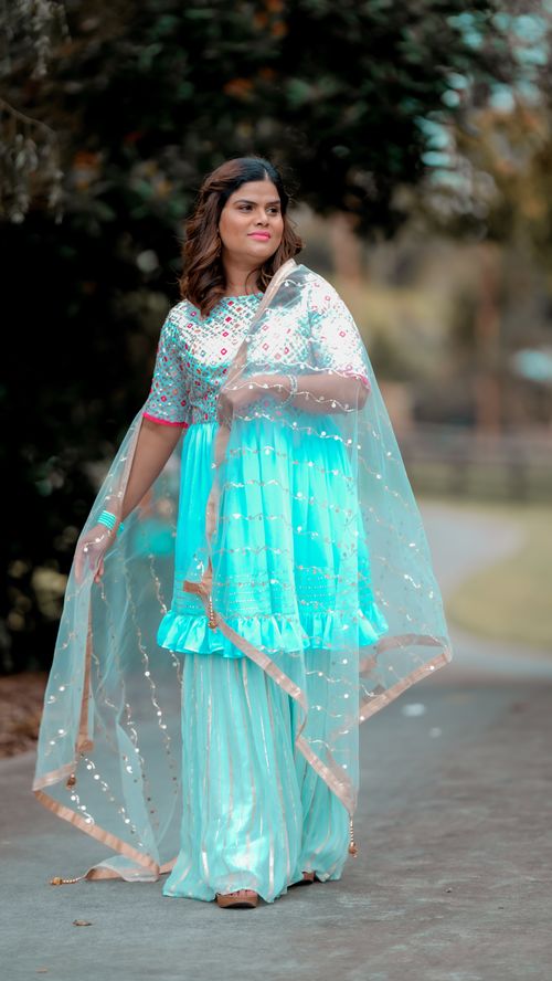 Free Woman in a vibrant traditional dress holding a dupatta outdoors. Stock Photo