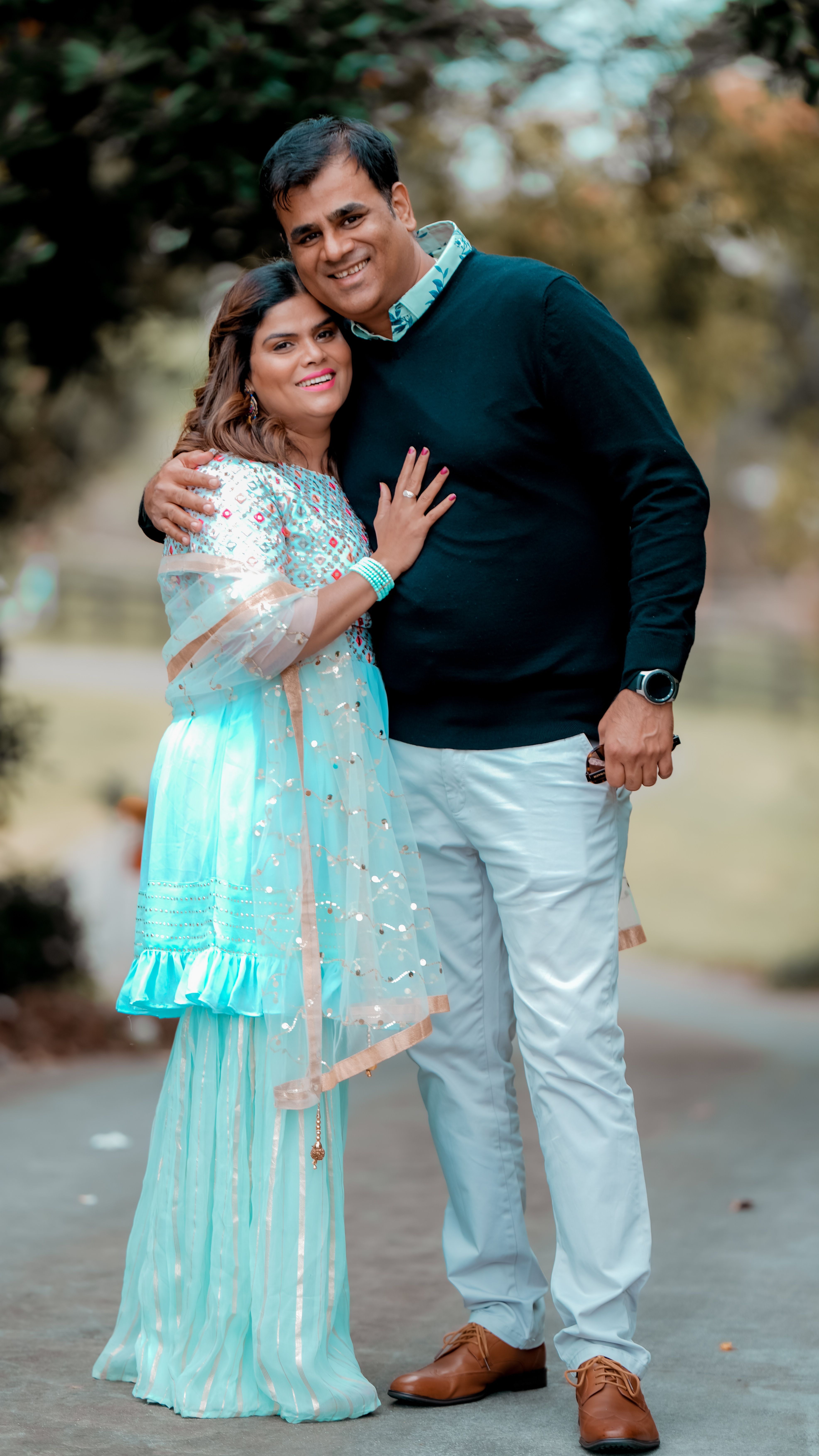 A couple lovingly embracing in stylish attire, showcasing romance and warmth outdoors.