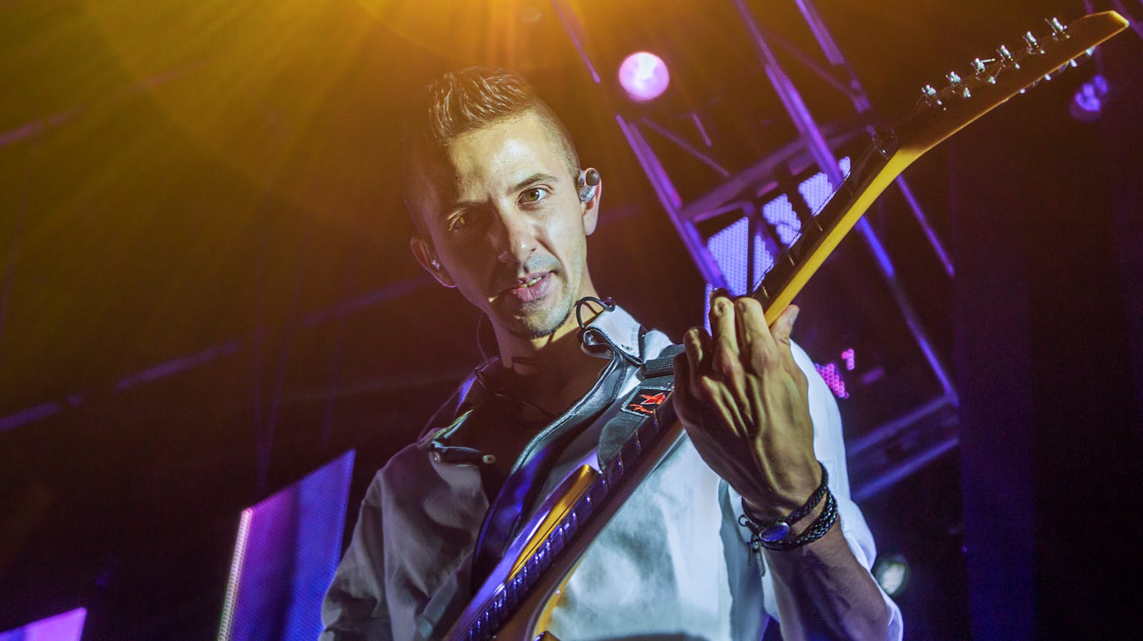 Guitarist performing on warmly lit stage with high energy