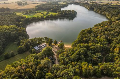 Free A breathtaking aerial view of a lush green landscape surrounding a picturesque lake during summer. Stock Photo