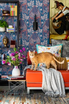 A vibrant living room featuring a cat, floral decor, and artistic accents.