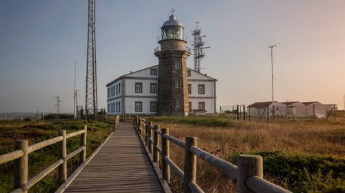 Free A beautiful coastal lighthouse with a boardwalk leading to it, captured at sunset. Stock Photo
