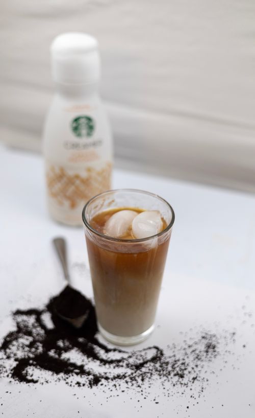 Free A close-up of iced coffee with cream and ice cubes, surrounded by ground coffee. Stock Photo