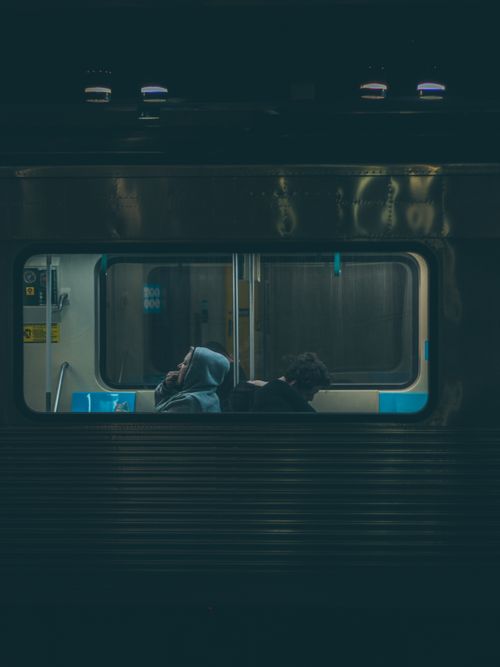 Free Two passengers sit in a dimly lit São Paulo subway train at night, lost in thought. Stock Photo