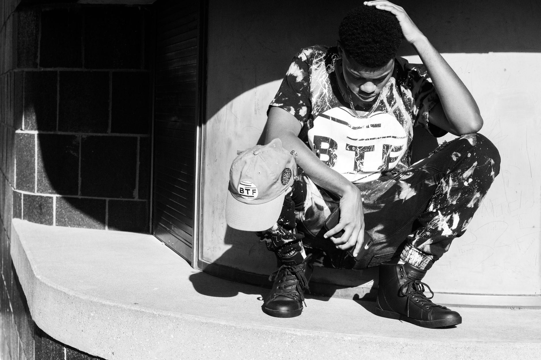 Black and white portrait of a man in stylish urban wear squatting in Washington, DC.